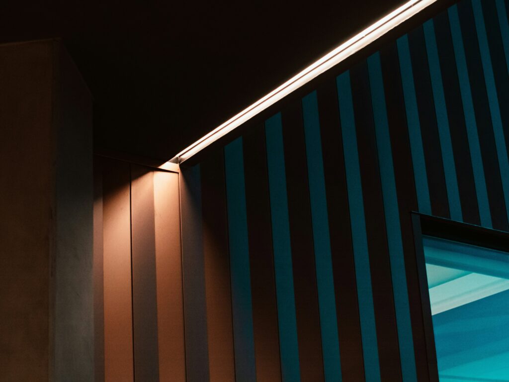 Recessed lighting casts a warm glow on a striped wall, creating a visually appealing contrast and enhancing the space