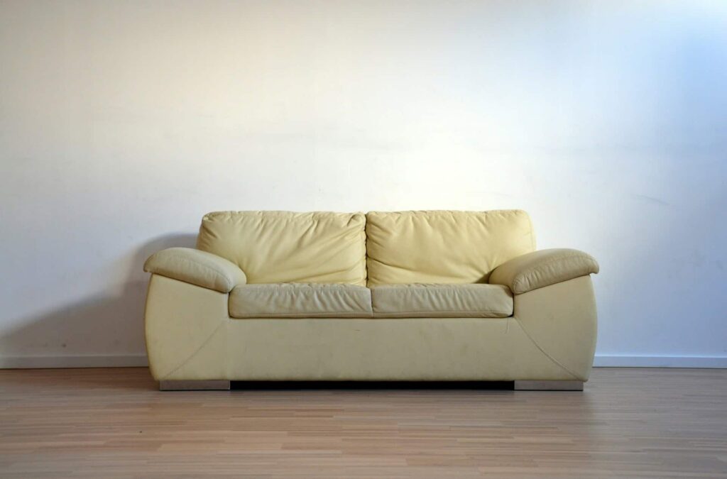 A bright empty room featuring a white wall and the best sofa, a vibrant yellow couch, creating a cheerful atmosphere.