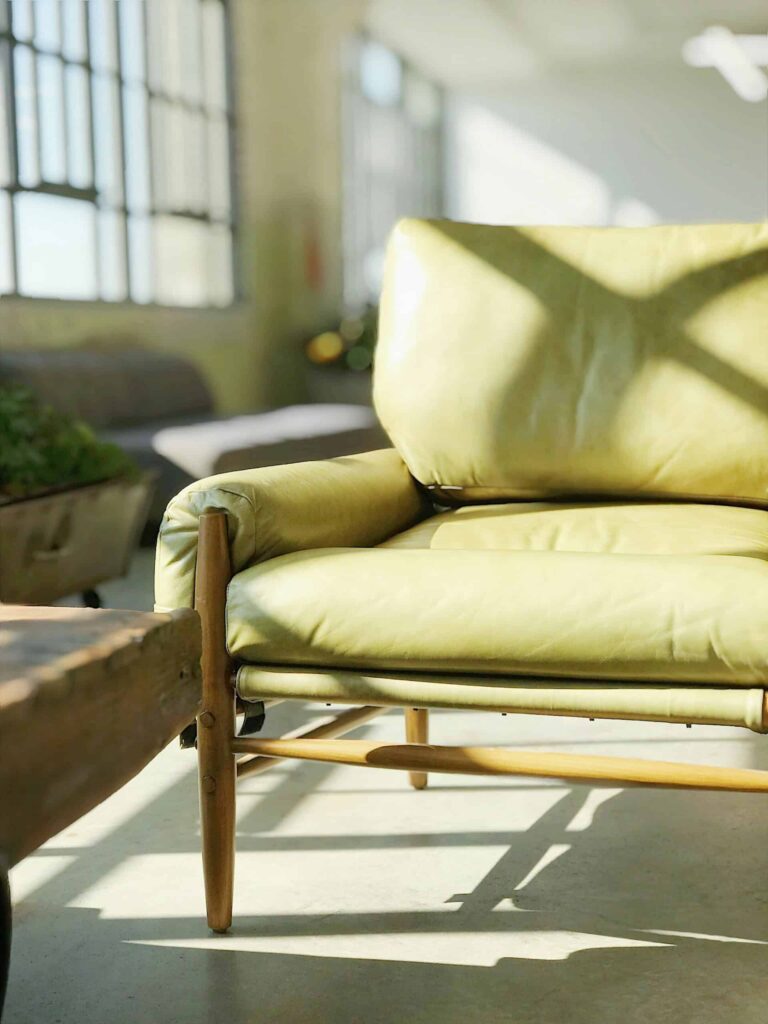 Handcrafted items include a green leather chair set against an industrial backdrop, highlighting its distinctive craftsmanship