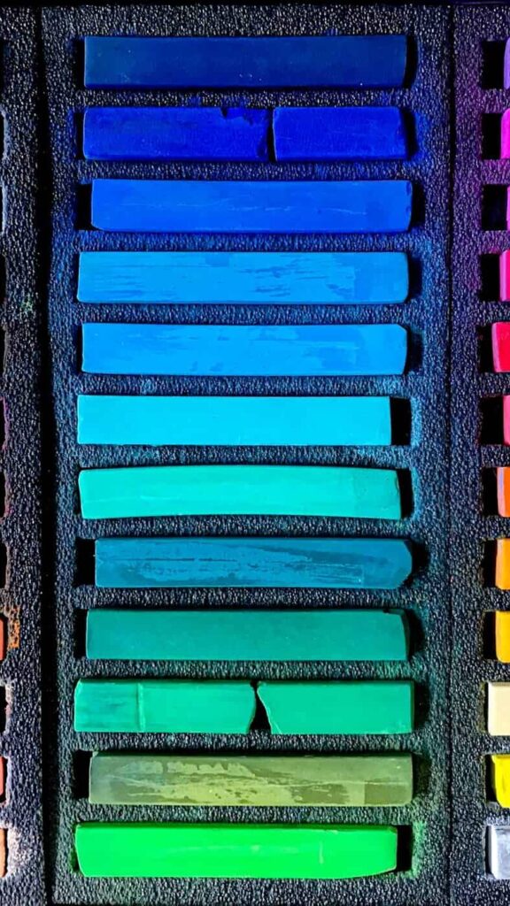 A box filled with an array of colored pencils in various vibrant hues, neatly arranged for artistic use.