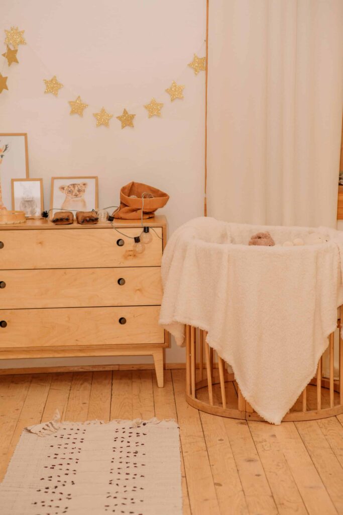 A cozy baby room featuring a crib, dresser, and warm wooden flooring, creating a welcoming atmosphere.