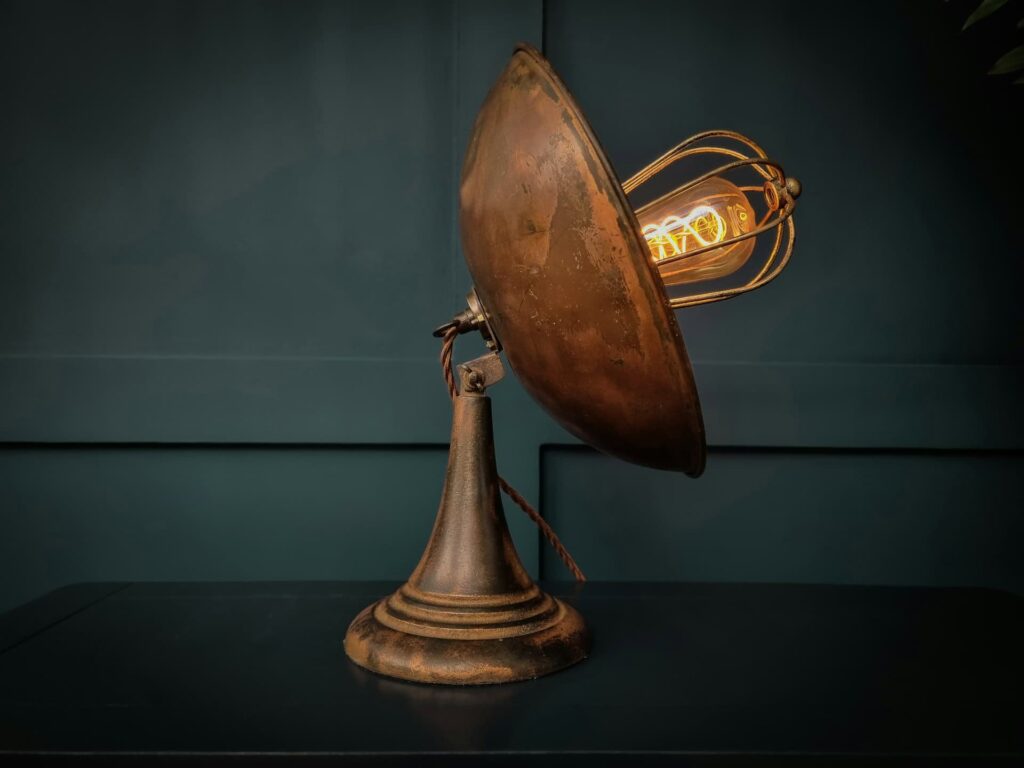 An antique lamp featuring a classic design with a bulb positioned at the top, illuminating its vintage charm.