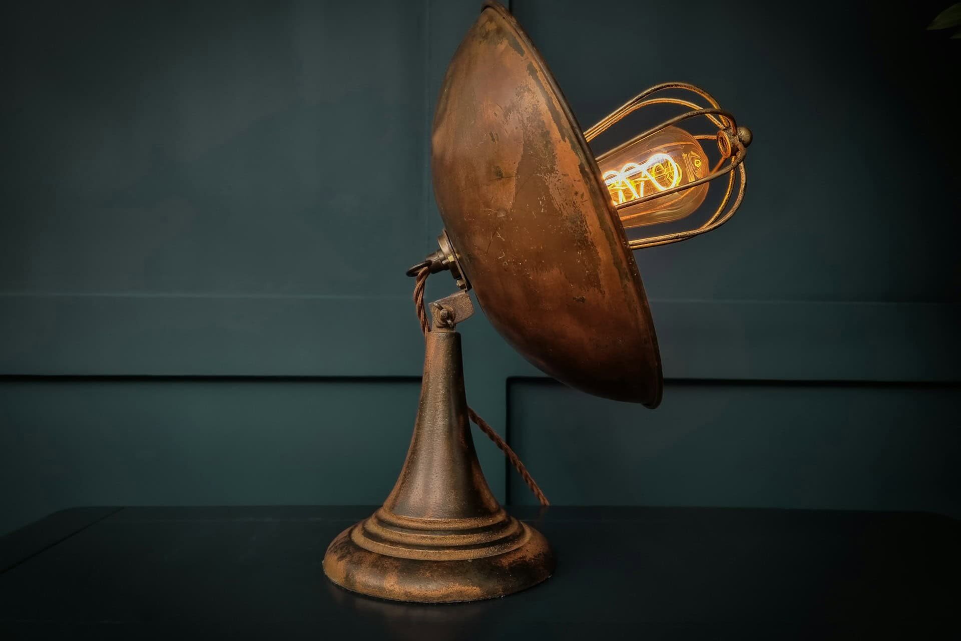 An antique lamp featuring a classic design with a bulb positioned at the top, illuminating its vintage charm.