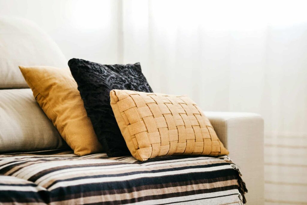 A couch adorned with decorative pillows and a striped blanket, creating an inviting and stylish living space.