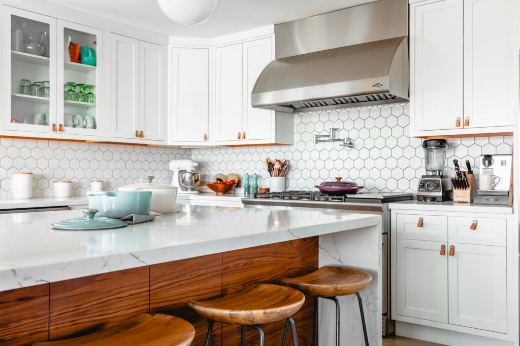 A stylish kitchen showcasing white cabinetry paired with wooden stools, enhancing the space's warmth and elegance.