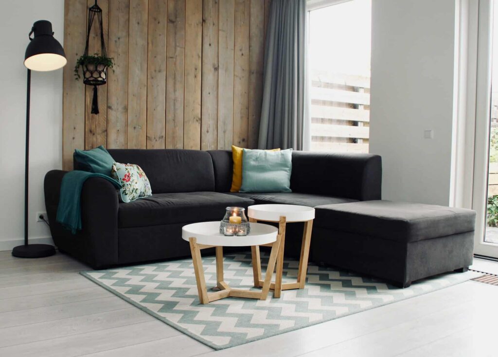  A stylish living room featuring the best sofa, a black couch, complemented by a soft white rug beneath it.